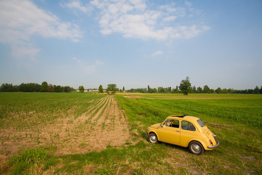Old retro little yellow car stands in a field in Europe Italy 2013