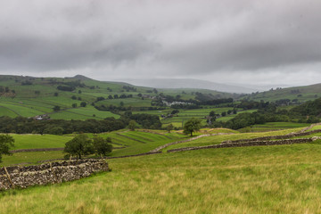 Yorkshire landscape with green fields, dry stone walls and dark clouds