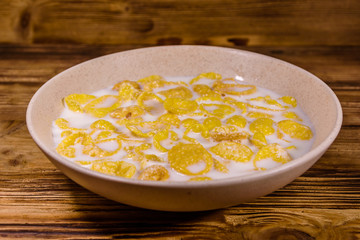 Ceramic plate with cornflakes and milk on a wooden table. Healthy eating