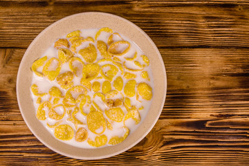 Ceramic plate with cornflakes and milk on a wooden table. Healthy eating. Top view