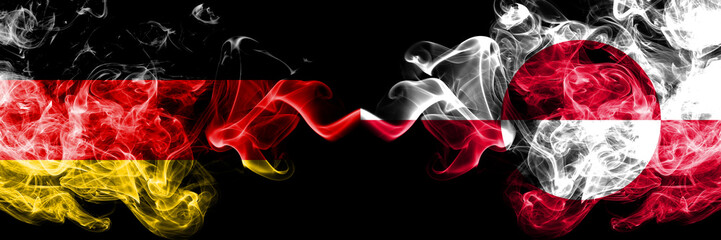 Germany vs Greenland smoky mystic flags placed side by side. Thick colored silky smoke flags of Deutschland and Greenland