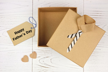 Happy Fathers Day card and opened shirt and tie gift box on a white wood background. Top view.