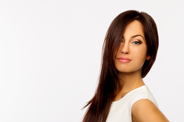 Portrait of beautiful young smiling woman with long brown hair on white background. Copy space