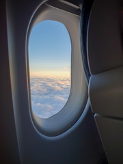 Fototapeta premium The view outside an airplane window with the sun setting and the clouds in the background