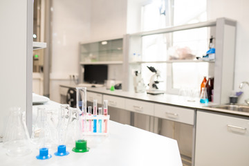 Colorful liquids in test tubes, empty beakers and stands placed on table in university laboratory