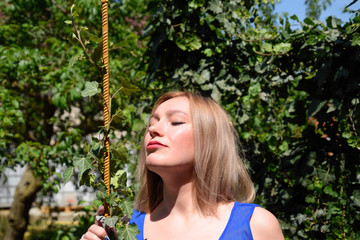 Portrait of a girl in a blue dress on a background of green arbor of ivy.
