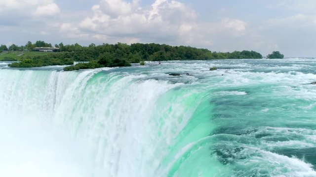 NIAGARA FALLS, US-CANADA BORDER. Aerial 4K slow motion shot of rushing water of the iconic waterfalls. Revers