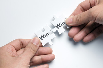 Hand putting two pieces puzzle together with word win win situation