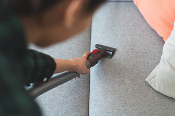 Person doing housework and cleaning sofa.