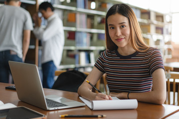 female asian student studying and reading book in library