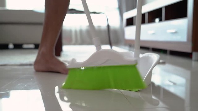 portrait a man cleaning living room with broom in the morning