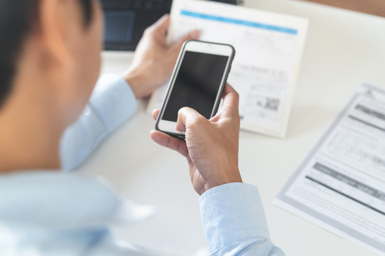 Above View Of Person Paying Bills Via Mobile Phone Banking Application.