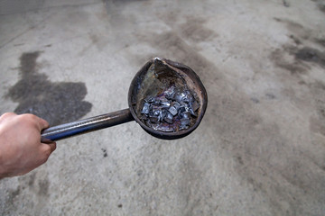 Close-up of a blacksmith man holding in his hand a metal pan with a melted lead in the workshop, top view.Iron and steel industry - Powered by Adobe