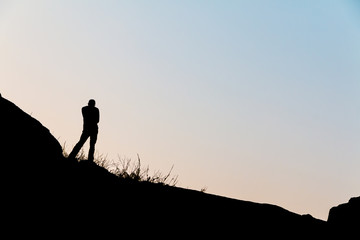 Silhouette men on the hill at sunset time.
