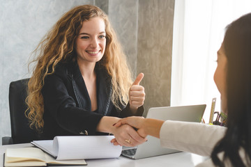 Businesswoman shaking hands with supplier and thumb up for good offer deal.
