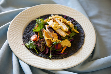 Black charcoal wrap with vegetables and chicken schnitzel