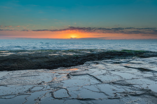 Rock Platform Sunrise Seascape with Light Smattering of Clouds