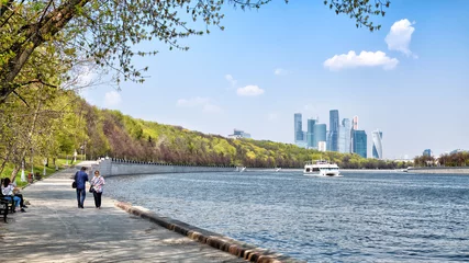 Plexiglas foto achterwand moscow city russia skyline and leisure boat on water of moskva river with scenery of town park embankment people walking relaxing on bench with city business skyscrapers landscape background 4K UHD © vaalaa