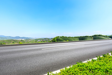 Fototapeta premium Country road and green mountains natural landscape under the blue sky