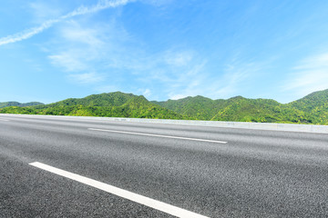 Fototapeta premium Country road and green mountains natural landscape under the blue sky