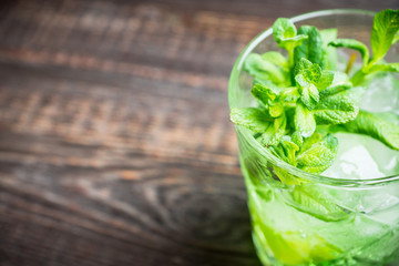 Summer old fashioned beverage with melon liqueur and mint leaves. Selective focus. Shallow depth of field.