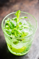 Summer old fashioned beverage with melon liqueur and mint leaves. Selective focus. Shallow depth of field.