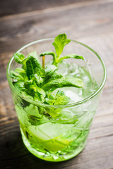 Summer old fashioned beverage with melon liqueur and mint leaves. Selective focus. Shallow depth of field.