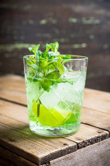 Summer old fashioned beverage with melon liqueur and mint leaves. Selective focus. Shallow depth of field.