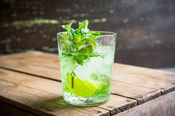 Summer old fashioned beverage with melon liqueur and mint leaves. Selective focus. Shallow depth of field.