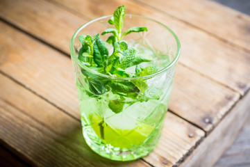 Summer old fashioned beverage with melon liqueur and mint leaves. Selective focus. Shallow depth of field.