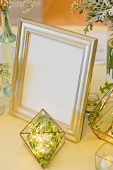 The stylish interior with mock up photo frame, leafs, plant, fairy lights and candle light.