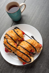 fresh croissant on the table, with hot tea, strawberries and bananas, delicious breakfast