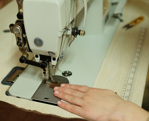 Closeup on young woman sewing leather handbag