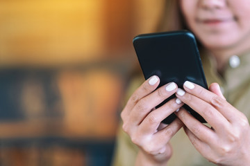 Closeup image of a woman holding and using mobile phone