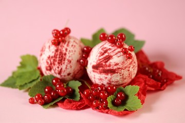bath bomb with berries extract.red striped bomb for a bath set and red currant berries on a pink...