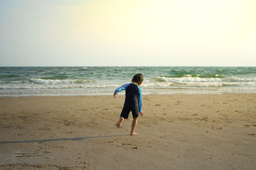 Kid in swimming suite is running into sea