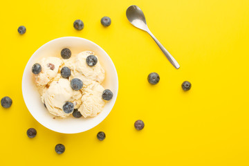 ice cream with blueberries, on a white background with a spoon. on a yellow background, with space, summer mood