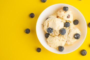 ice cream with blueberries, on a white background with a spoon. on a yellow background, with space, summer mood