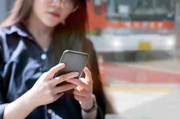 Cropped image of young asian woman using smartphone outdoors.