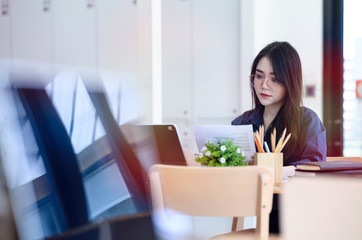 Young woman working with laptop and paperwork at co working space.