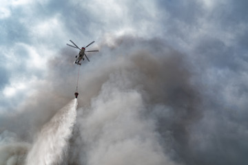 Fototapeta na wymiar Rescue helicopter drops water extinguishes the fire
