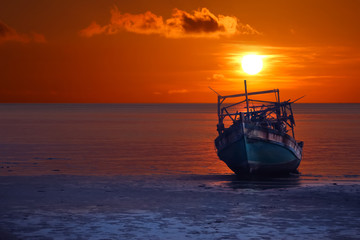 Naklejka na ściany i meble Old broken boat abandoned on the beach at sunset ,Red sky