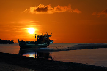 Naklejka premium Old broken boat abandoned on the beach at sunset ,Red sky