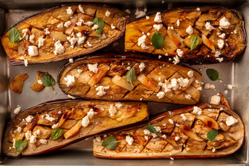 Vegan Italian food. Baked eggplants with organic herbs, garlic, and lactose-free cheese, shot from the top in a baking sheet