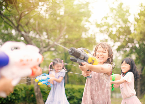 happy little girls playing with water guns on summer