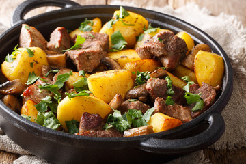 Fried potatoes with meat and mushrooms close-up on the table, rustic. horizontal