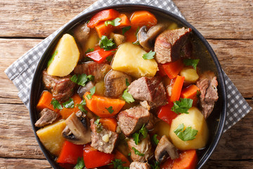 pork stew with mushrooms, potatoes, carrots and peppers close-up on a plate. horizontal top view