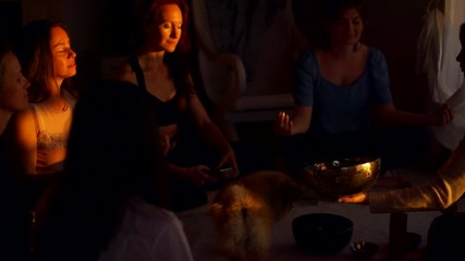 Group practice of Tibetan singing bowls indoors at sunset. People in relaxing meditation