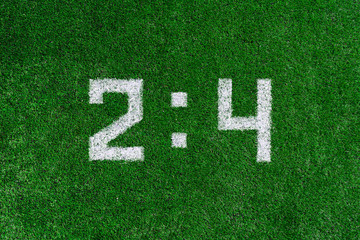 Football score.White numbers two and four are drawn on the green grass