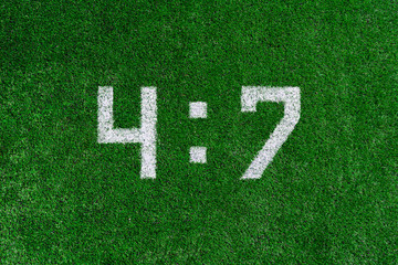 Football score.White numbers four and seven are drawn on the green grass,creative scoreboard